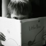grayscale photo of boy holding book