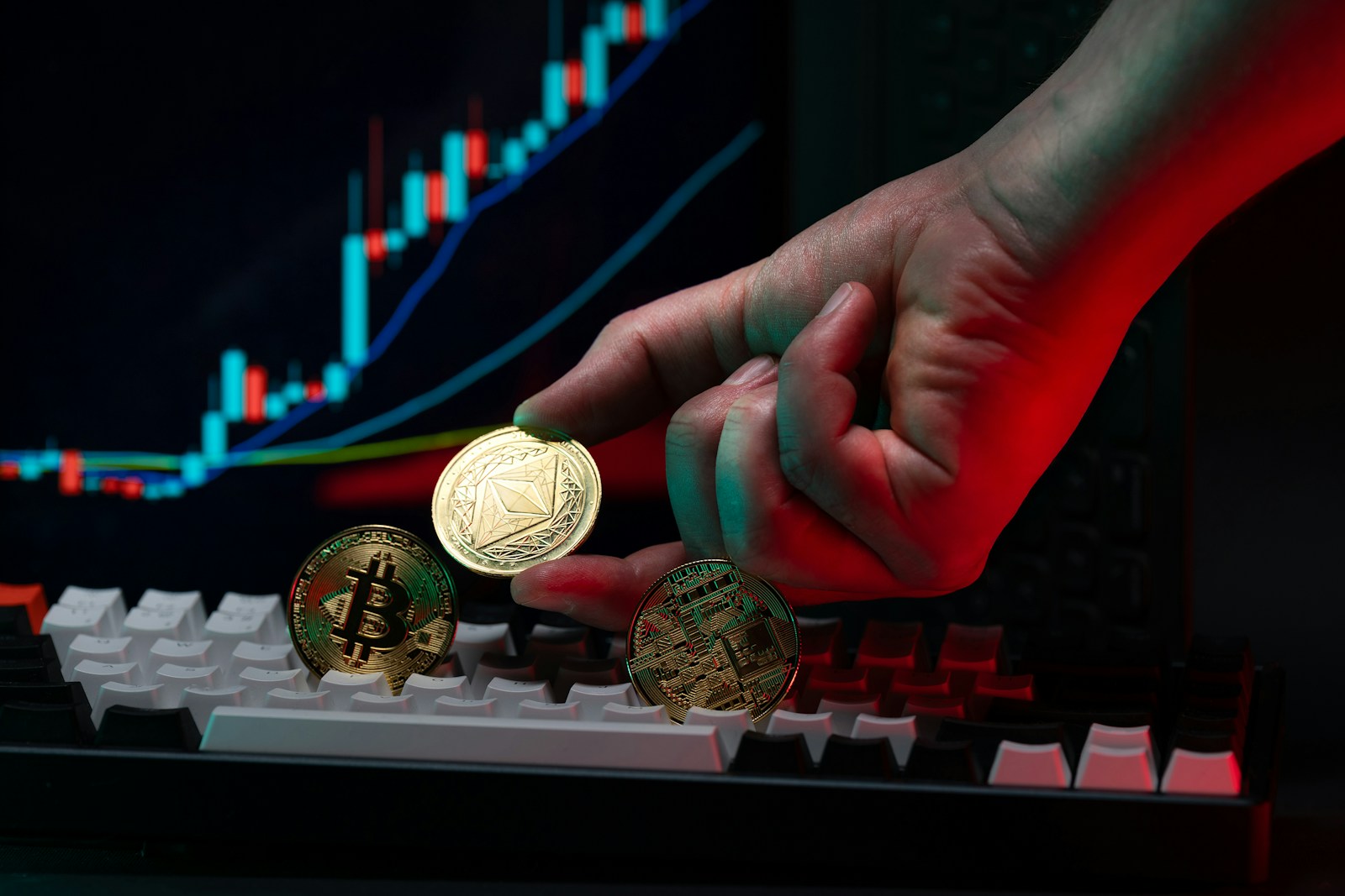 A person holding a coin in front of a computer keyboard